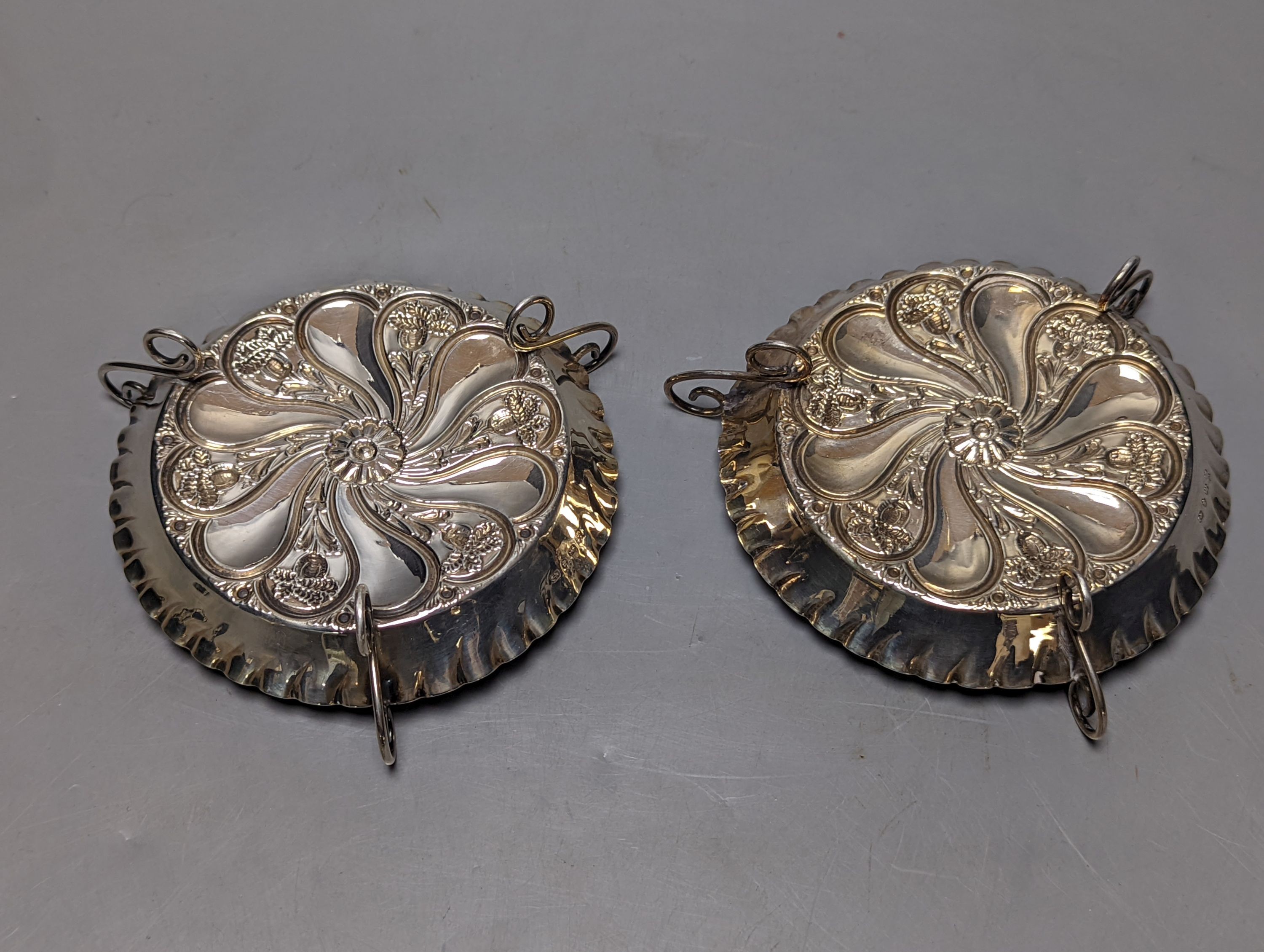 A pair of late Victorian repousse silver tri-handled shallow nut dishes, Vale Brothers & Serman, Birmingham, 1898, 13.7cm, 135 grams.
